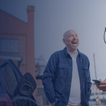 Three people stand next to charging EV