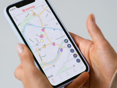 Lifestyle image of a person holding their phone, showing the Zapmap app