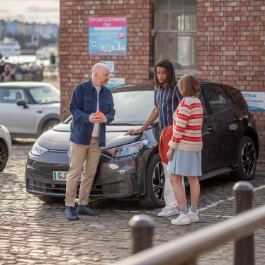 Three drivers stood talking by their EV