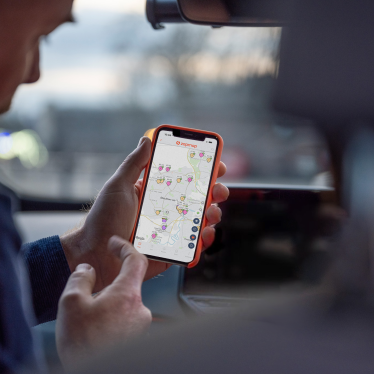 A photo of two people in a car, looking at the Zapmap app to find local EV chargers