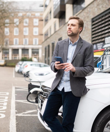 Business header - Olly leans on EV while charging
