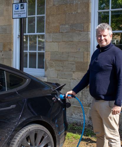 Man charging electric vehicle at Trinity Road car park, Cirencester