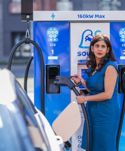 Woman in blue dress charging electric vehicle