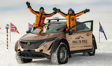 Nissan Ariya driving on road with mountains and forest in background
