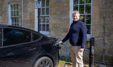 Man charging electric vehicle at Trinity Road car park, Cirencester